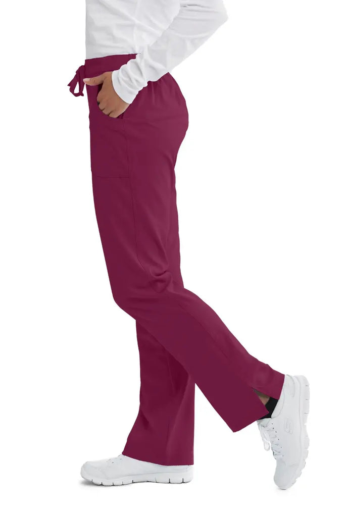The left side of the Skechers Women's Reliance Cargo Scrub Pants in Wine size Medium featuring a shaped flare leg with side slits.