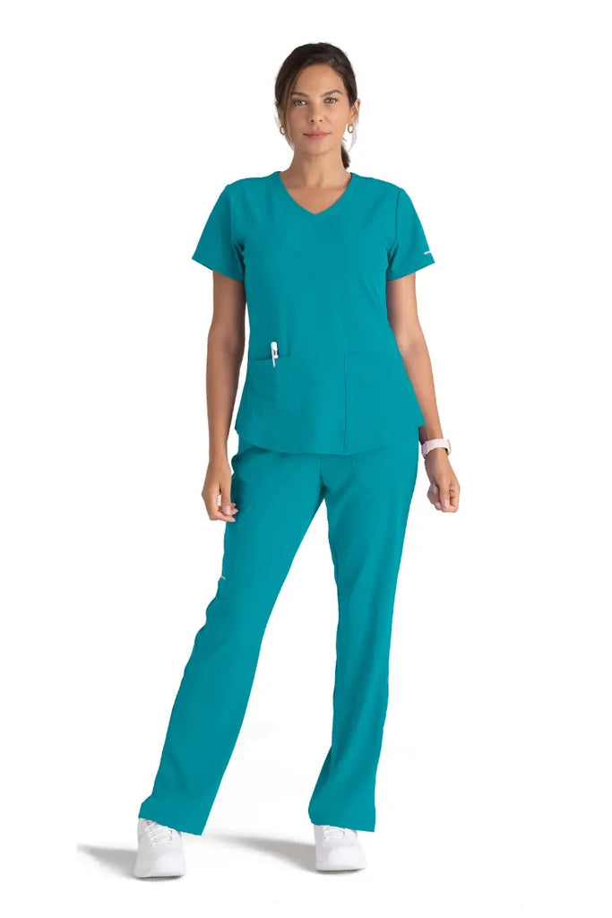A full body shot of a young female Dental Hygienist wearing Skechers Women's scrub uniform in Teal.