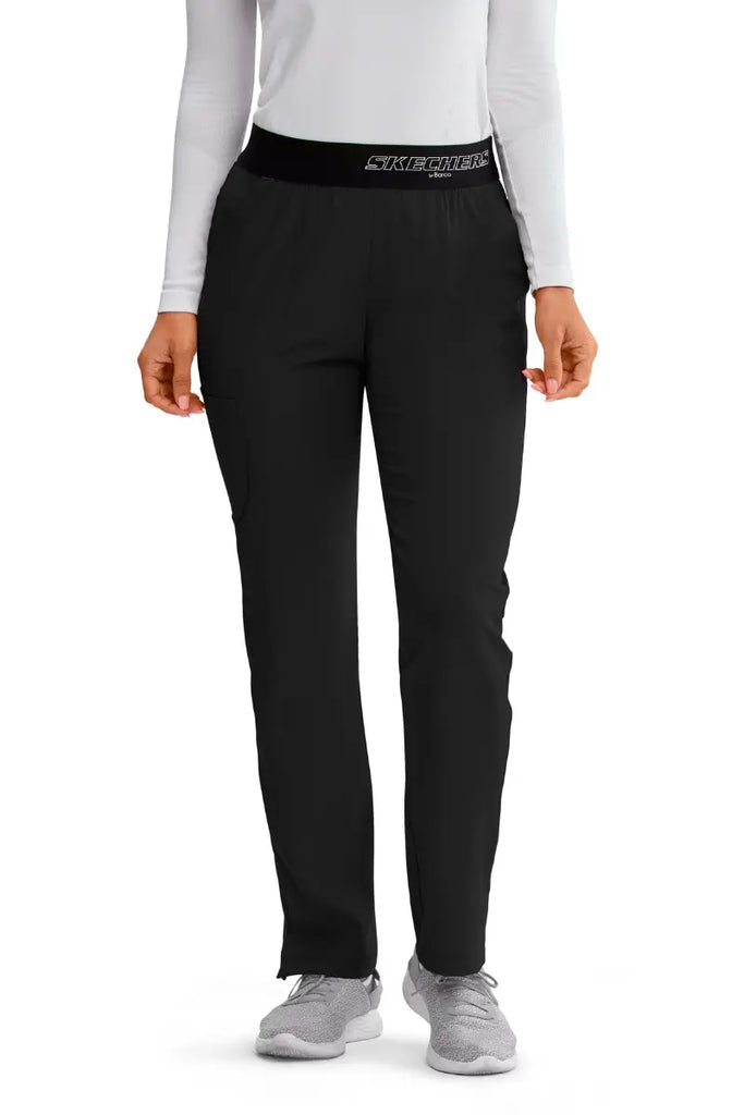 The front of the Skechers Women's Vitality Scrub Pants in Black featuring a fully elastic waistband with the Skechers logo printed on the front.
