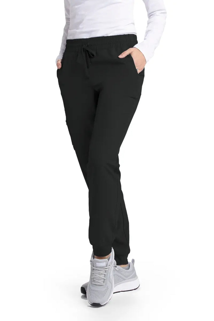 A young female Physical Therapist wearing a pair of the Skechers Women's Theory Scrub Joggers in Black size Medium featuring two front slanted pockets.