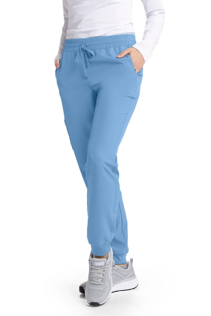 A young female Dental Assistant wearing a pair of the Skechers Women's Theory Scrub Joggers in Ceil Blue size Medium featuring two front slanted pockets.