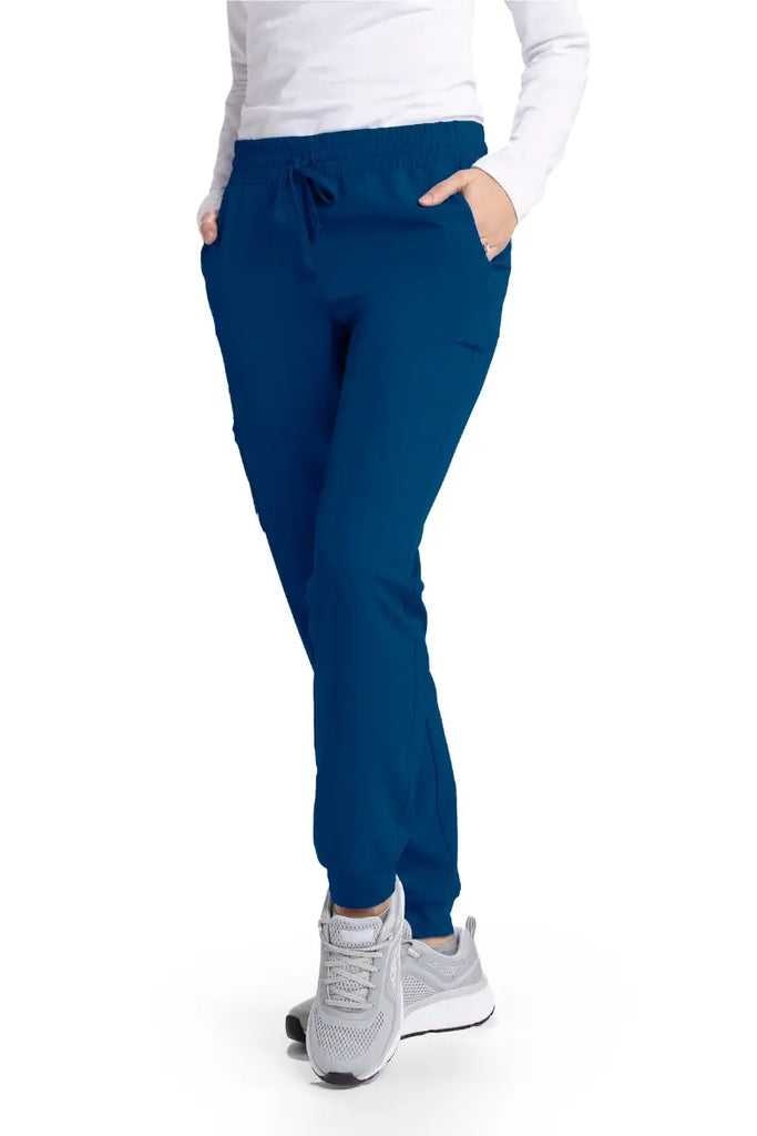 A young female LPN wearing a pair of Skechers Women's Theory Joggers in Navy size large featuring two front slanted pockets.