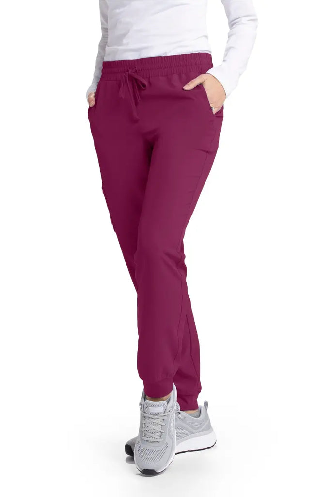 A female Cardiovascular Nurse wearing a pair of the Skechers Women's Theory Joggers in Wine size Medium featuring a modern fit.