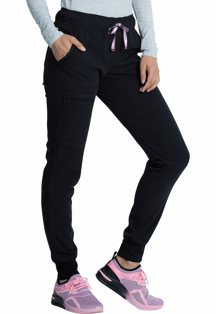 A young female Medical Assistant wearing a Vince Camuto Women's Mid Rise Drawstring Jogger in Black size 3XL featuring an outside, zipper cargo pocket on the wearer's left side.