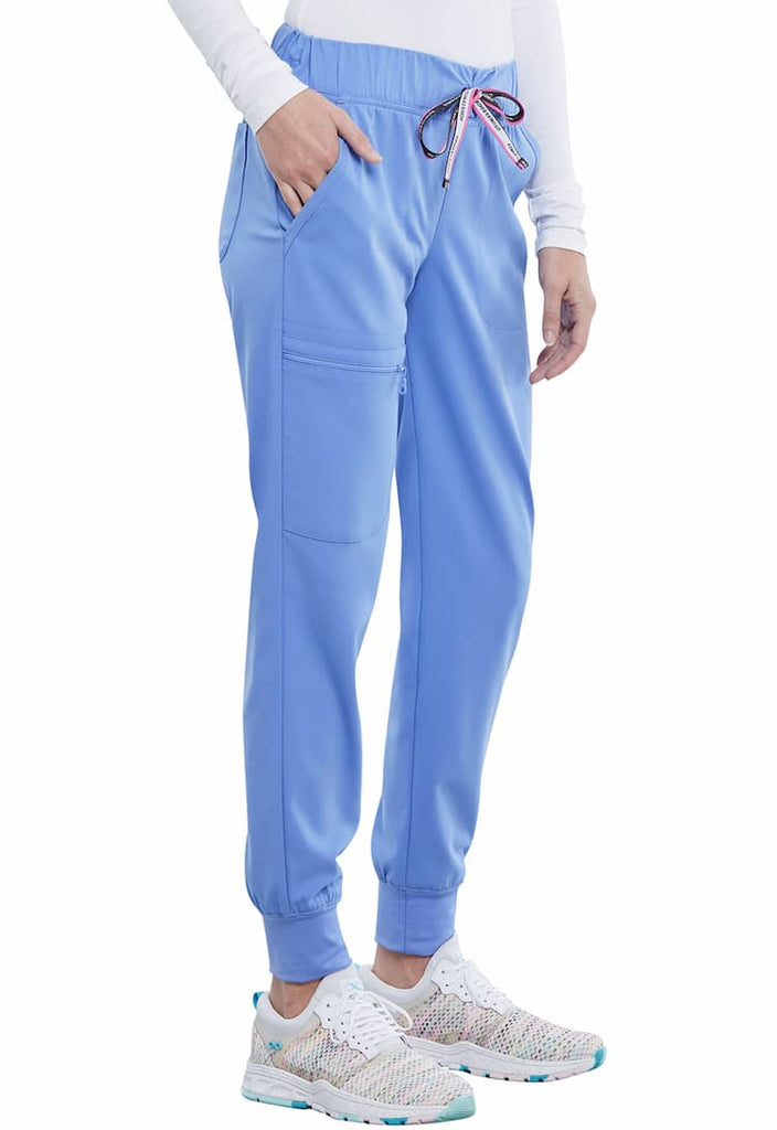 A young female Medical Assistant wearing a Vince Camuto Women's Mid Rise Drawstring Jogger in Ceil size Small featuring an outside, zipper cargo pocket on the wearer's left side.