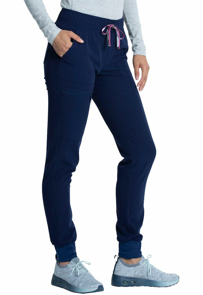 A young female Medical Assistant wearing a Vince Camuto Women's Mid Rise Drawstring Jogger in Navy size Medium featuring an outside, zipper cargo pocket on the wearer's left side.