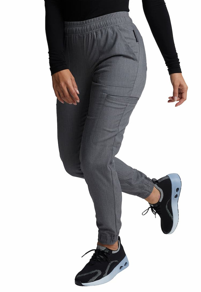 A young female Cardiologist wearing a pair of Vince Camuto Women's Mid Rise Scrub joggers in Heathered Charcoal size Medium Petite featuring a 29" inseam.