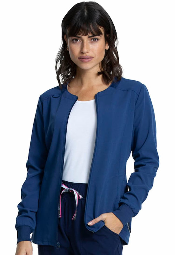 A young female Physical Therapist wearing a Vince Camuto Women's Zip Front Scrub Jacket in Navy size Large featuring knit insets at the neckline & cuffs.