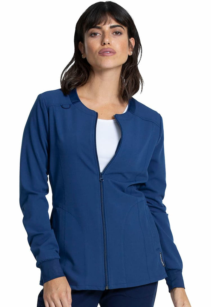 A young female Physician's Assistant wearing a Vince Camuto Women's Zip Front Scrub Jacket in Navy size 3xl featuring a total of 3 pockets.