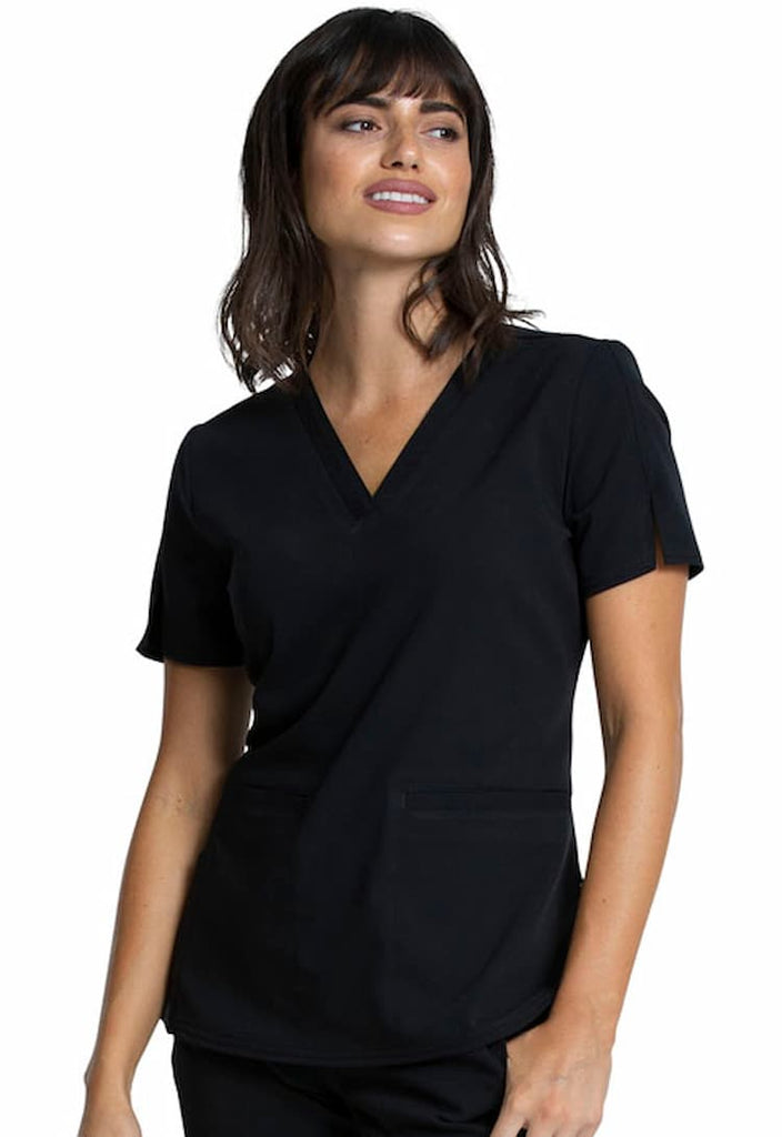A young female Registered Nurse wearing a Vince Camuto Women's V-neck Scrub Top in Black size XS featuring 2 front patch pockets.