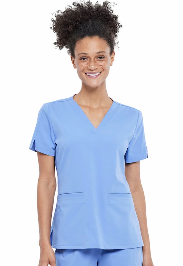 A female Surgical Assistant wearing a Vince Camuto Women's V-neck Scrub Top in Ceil size Large featuring side slits for additional mobility throughout the day.