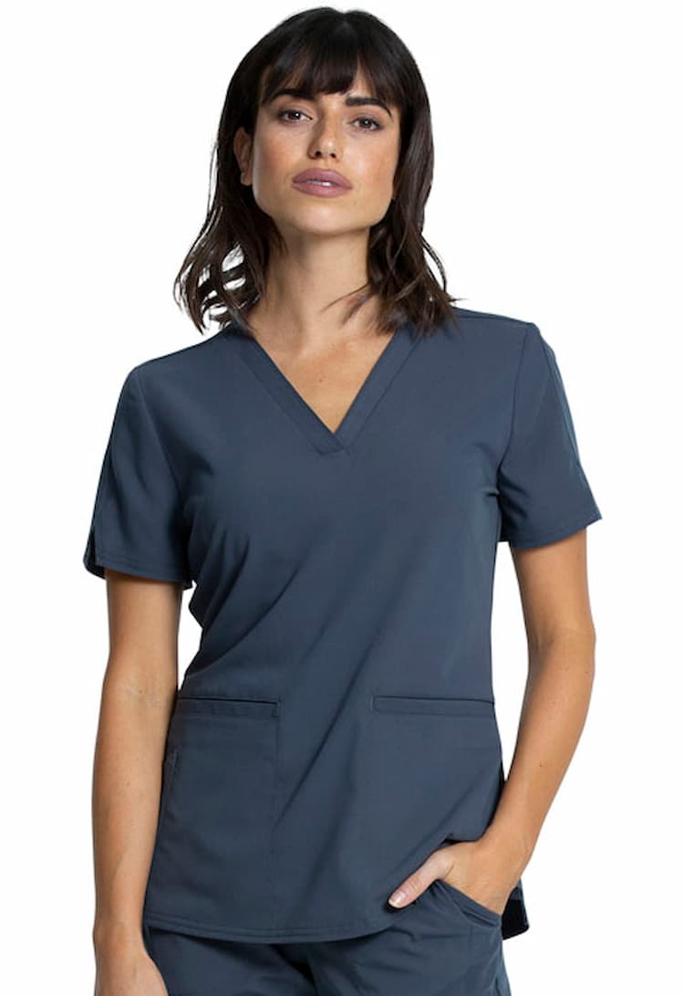 A young female Registered Nurse wearing a Vince Camuto Women's V-neck Scrub Top in Pewter size XS featuring 2 front patch pockets.