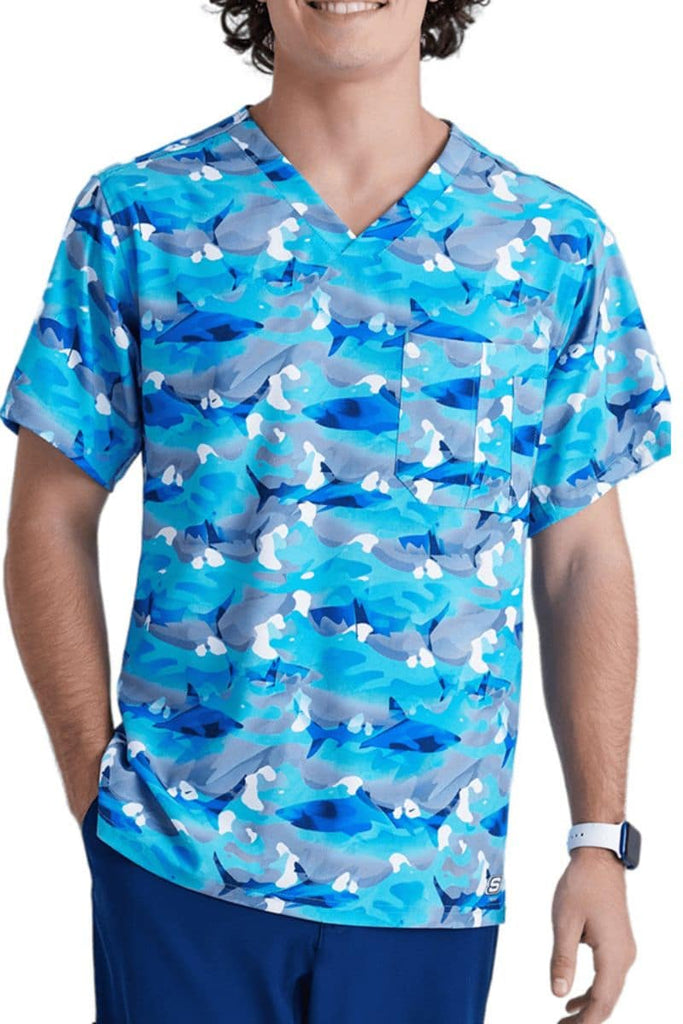 A young male Pediatric Nurse wearing a Skechers Men's Structure Crossover V-Neck Printed Scrub Top in "Wild Tide" featuring a a durable yet breathable blend of polyester and spandex.