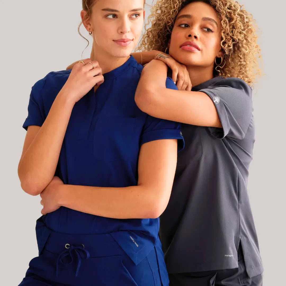 Two female nurses showcasing available scrubs from Scrub Pro's Women's Scrubs collection on a light grey background.