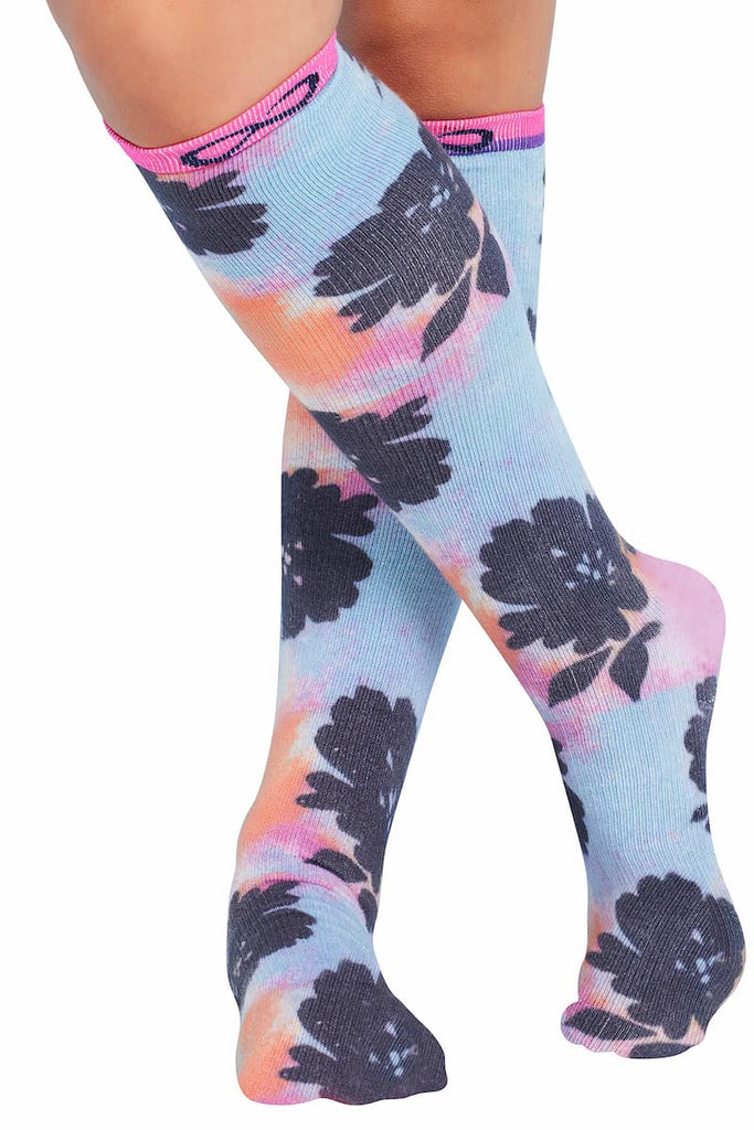 The front of the Infinity Women's Kickstart Compression Socks in Artistic Blooms featuring a stylish tie dye themed print with navy flowers scattered across a light blue, orange and pink background.