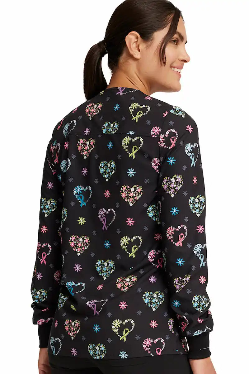 A young female Labor and Delivery Nurse wearing a Cherokee Women's Printed Snap Front Scrub Jacket in "Care Flor-all" size Medium featuring a center back length of 28.5" for optimal coverage.