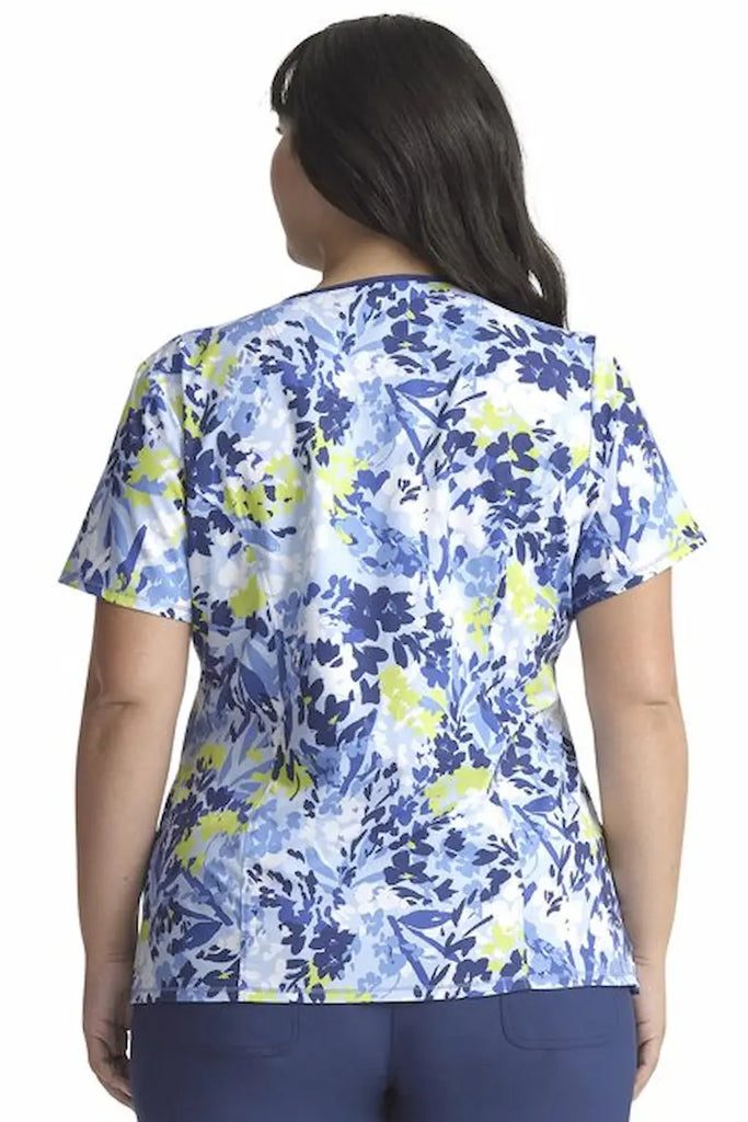 A young female Oncology Nurse wearing a Cherokee Infinity Women's Mock Wrap Printed Scrub Top in "Brushstroke Buds" size 2XL featuring a center back length of 26".