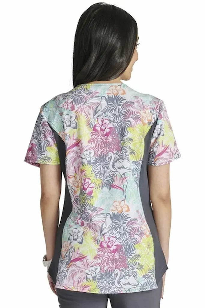 An image of the back of a young female Labor and Delivery Nurse wearing a Cherokee iFlex Women's Knit Panel Printed Scrub Top in "Birds of Paradise" featuring a center back length of 25".