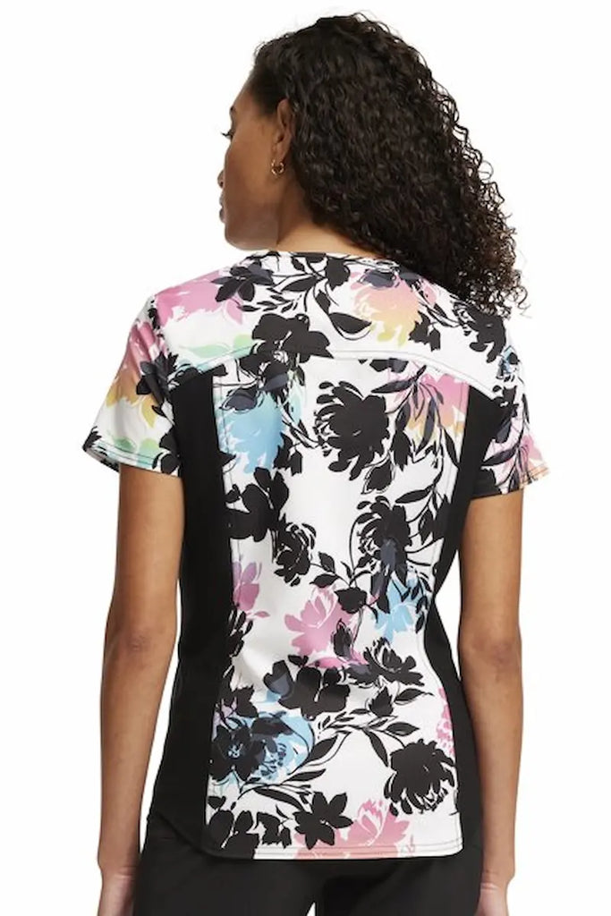 A young female Oncology Nurse wearing a Cherokee iFlex Women's V-neck Printed Scrub Top in "Garden Glow" size Medium featuring a center back length of 25" for optimal coverage.