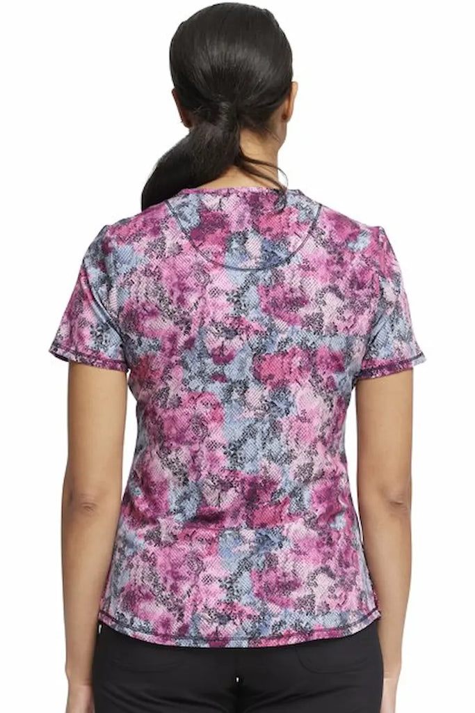 An image of the back of a young female Neonatal Nurse wearing a Cherokee Infinity Women's Round Neck Printed Scrub Top in "Hiss or Miss" featuring a center back length of 26" for optimal coverage.