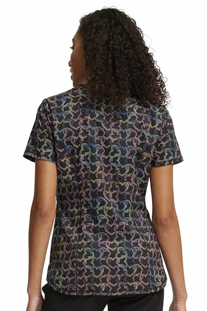 An image of the back of a young female Psychiatric Nurse wearing a Women's Printed Scrub Top from Cherokee Infinity in "Links of Love" featuring an an uplifting design with interconnected chains in vibrant colors, symbolizing hope, unity, and strength. 