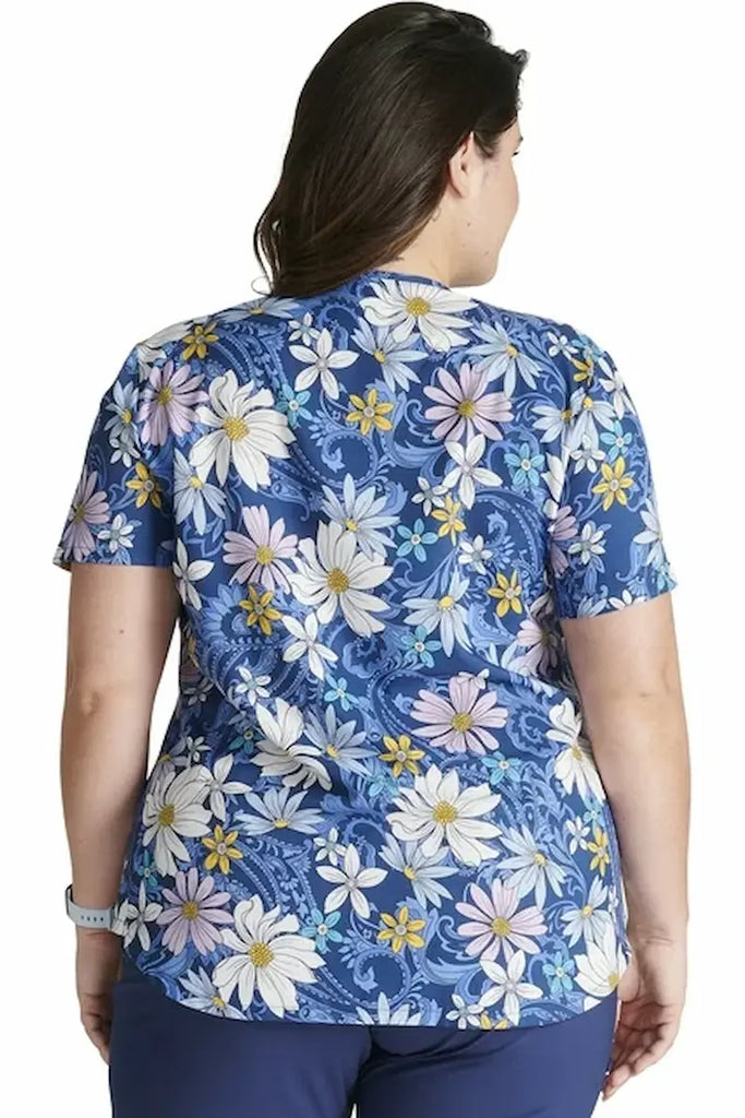 A young female Labor and Delivery Nurse wearing a Cherokee Women's V-neck Printed Scrub Top in "Prairie Paisley" size 2XL featuring a rounded hem & side vents for a flattering and comfortable all day look and feel.