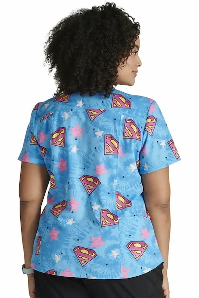 A young female Neonatal Nurse wearing a Tooniforms Women's Rounded V-neck Printed Scrub Top in "Symbol of Hope" in size 3XL featuring a center back length of 25" for optimal coverage.