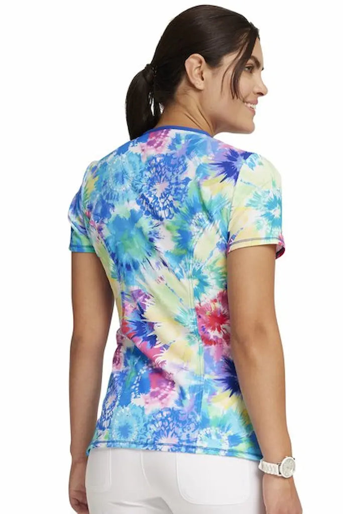 A young female Psychiatric Nurse wearing a Cherokee Infinity Women's Round Neck Printed Scrub Top in "Tie Dye Burst" size Large featuring a c enter back length of 26".