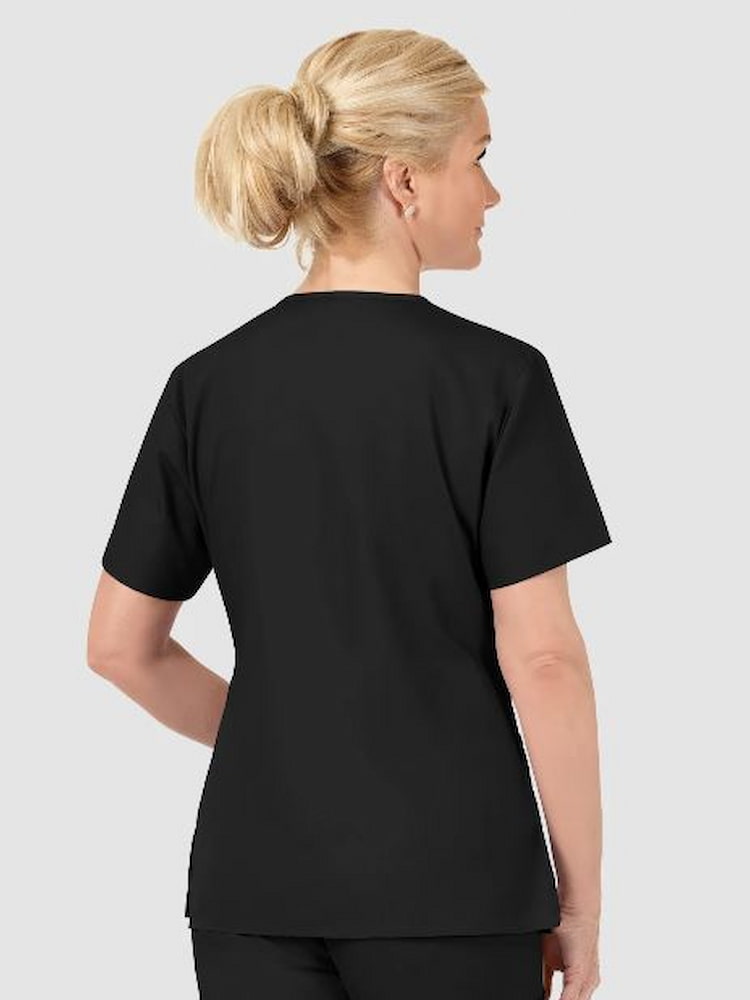 A middle aged female lab tech wearing a WonderWink Origins Women's Bravo V-neck Scrub Top in Black size Large featuring side slits on both sides.
