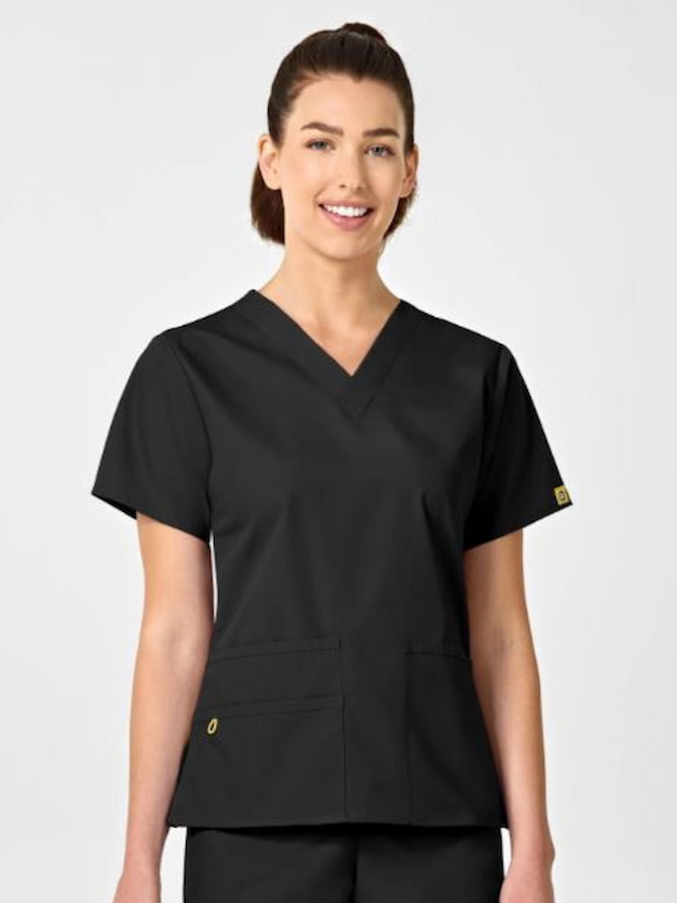 A young female licensed practical nurse wearing a WonderWink Origins Women's Bravo Scrub Top in Black featuring a modern fit, 5 total pockets & a soft poly cotton fabric.
