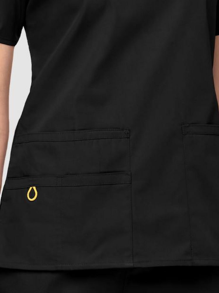 An up close image of the two lower pockets including one WonderWink signature triple pocket with hidden mesh pocket & signature ID bungee loop on the WonderWink Women's Bravo V-neck Scrub Top in Black.