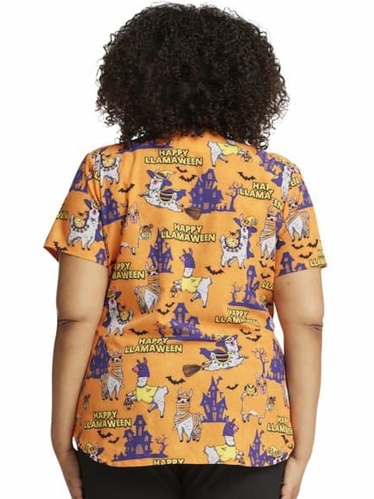 A young female Pediatric Nurse wearing a Cherokee Women's V-Neck Halloween Printed Scrub Top in "Happy Llamaween" featuring a center back length of 28.5".