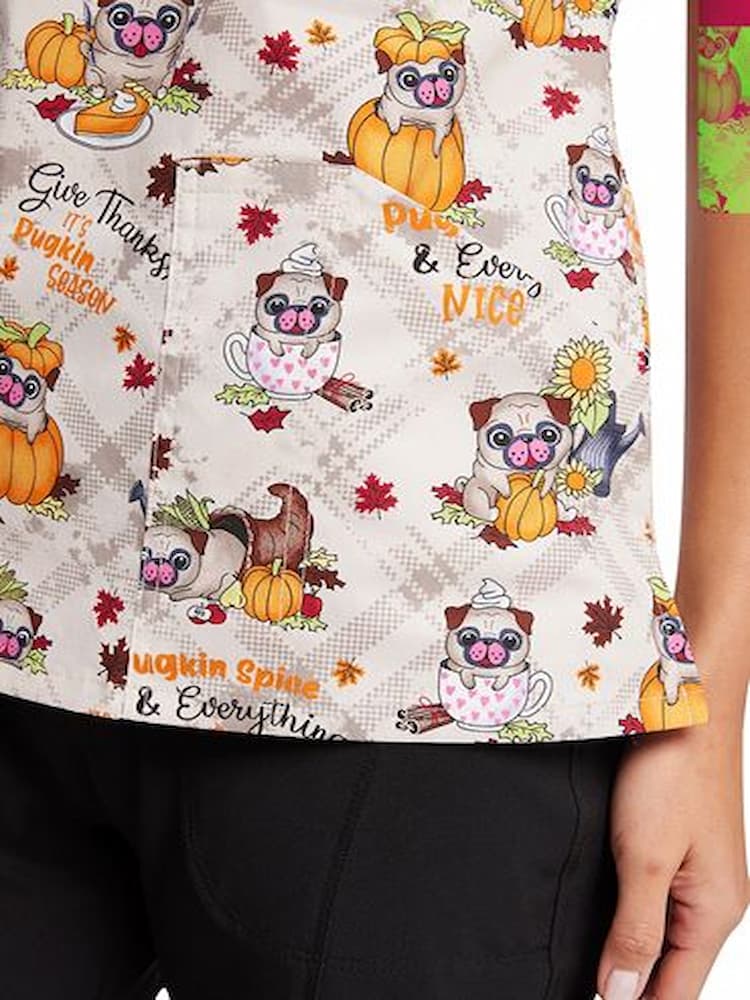 A close up shot of the left side front patch pocket on the Cherokee Women's Printed V-Neck Scrub Top in "Pugkin Spice" size Medium.