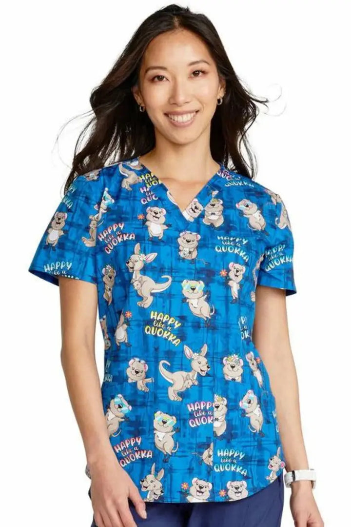 A young female Children's Nurse wearing the Happy as a Quokka Cherokee Women's V-Neck Print Scrub Top featuring short sleeves and a v-neckline.