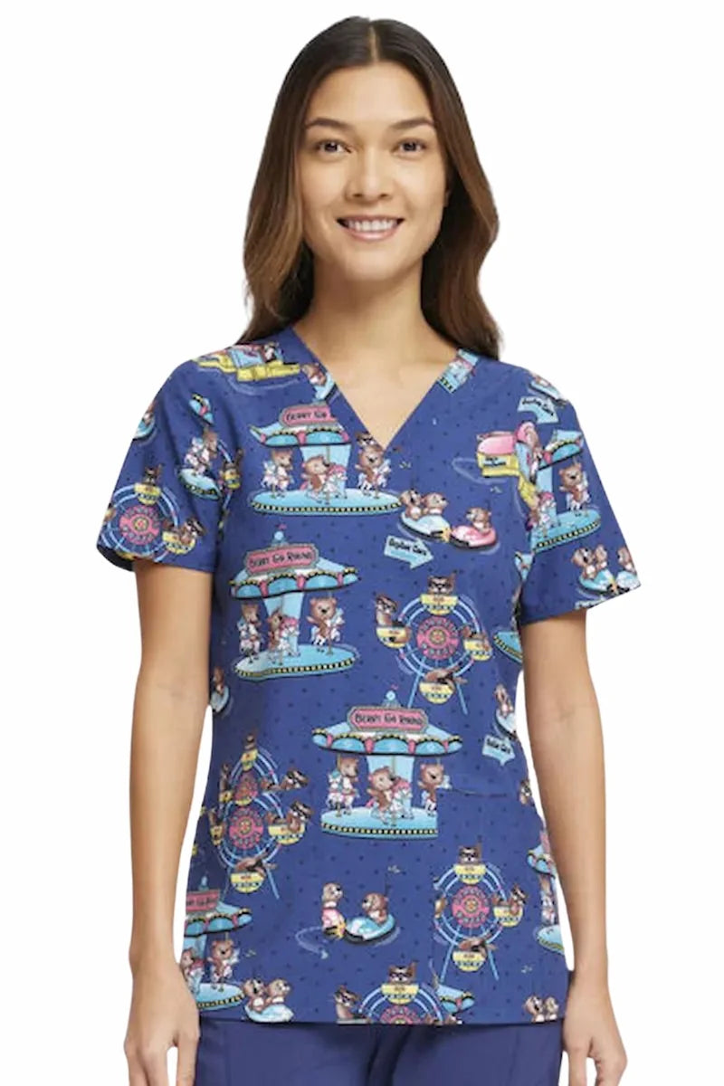 A young female children's nurse showcasing the front of the Cherokee Women's V-neck Print Top in Carnival Critters on a solid white background.