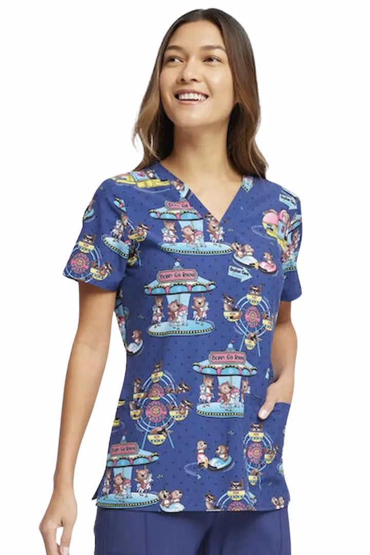 A young nurse displaying the right side of the Cherokee Women's V-neck Print Top in Carnival Critters size Large featuring short sleeves and a v-neckline.