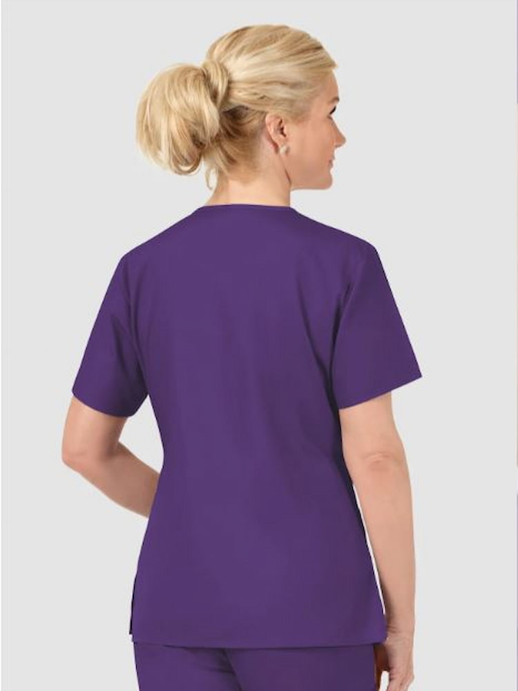 A young female Nursing Assistant wearing a WonderWink Origins Women's Barco V-neck Scrub Top in Eggplant size 3XL featuring a soft poly cotton fabric.