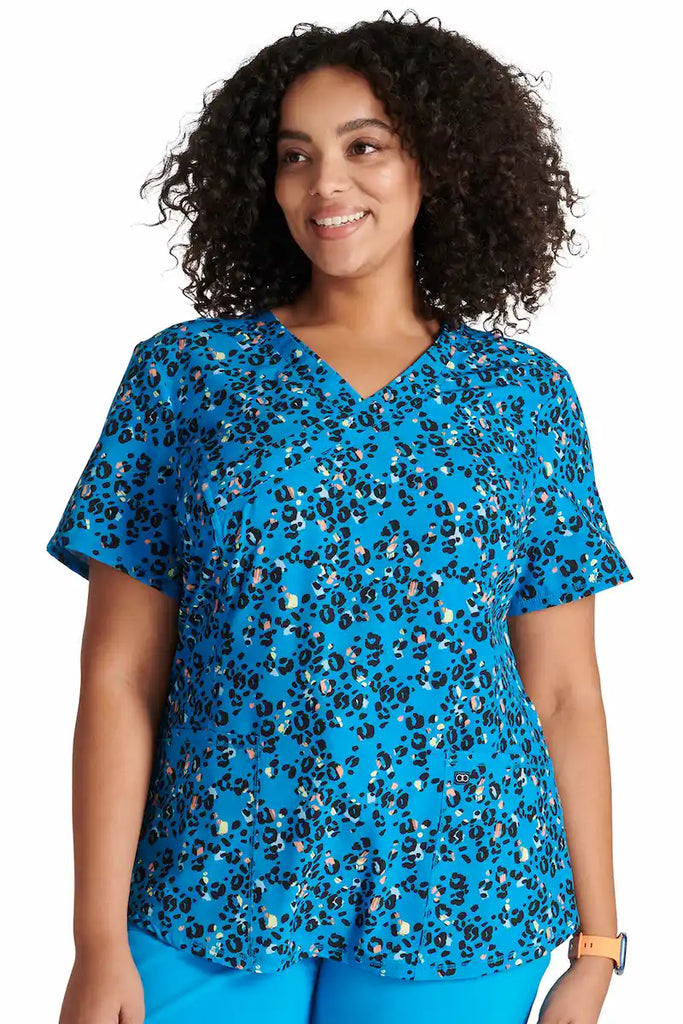 A young female Psychiatric Nurse wearing a Cherokee Women's Mock Wrap Scrub Top in "Leopard Pops' size 2XL featuring a soft and breathable fabric made of 92% polyester and 8% spandex.