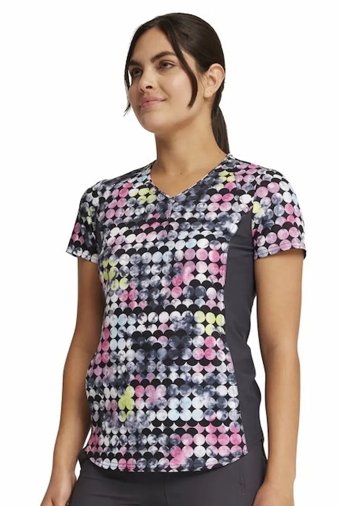 A young female Oncology Nurse wearing a Cherokee iFlex Women's V-neck Printed Scrub Top in "Dot's So Retro" size XL featuring knit side panels to provide a comfortable all day fit.