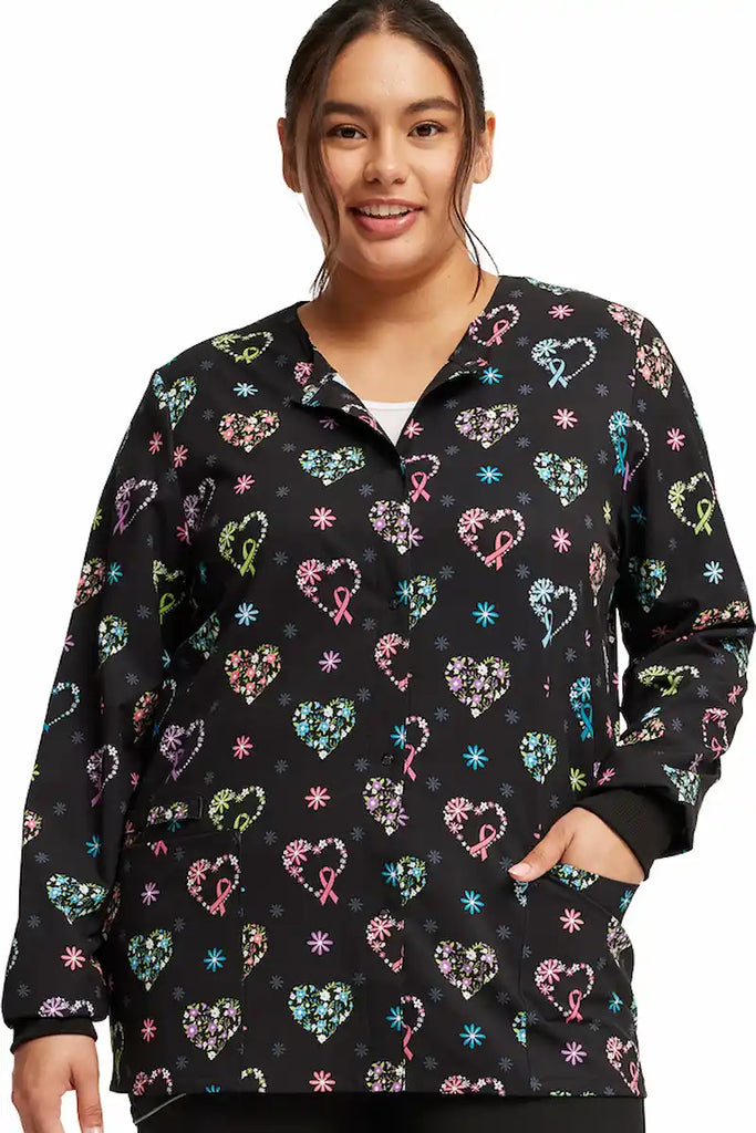 A young female Cherokee Women's Print Scrub Jacket in "Care Flor-All" size Large featuring rib knit cuffs.