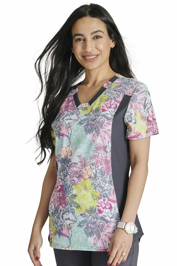 A female pediatric nurse wearing a Cherokee iFlex Women's Printed Scrub Top in "Birds of Paradise" size Small featuring a modern classic fit.