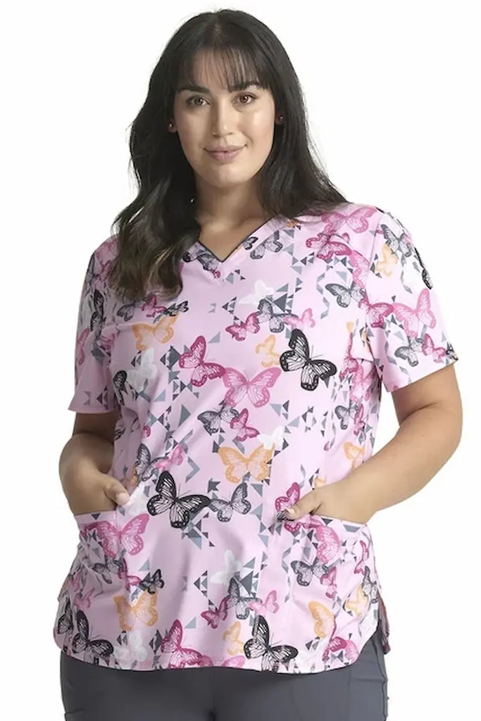 A young female Pediatric Nurse wearing a Cherokee Infinity Women's V-neck Printed Scrub Top in "Geo Flutter" size 2XL featuring a modern classic fit.