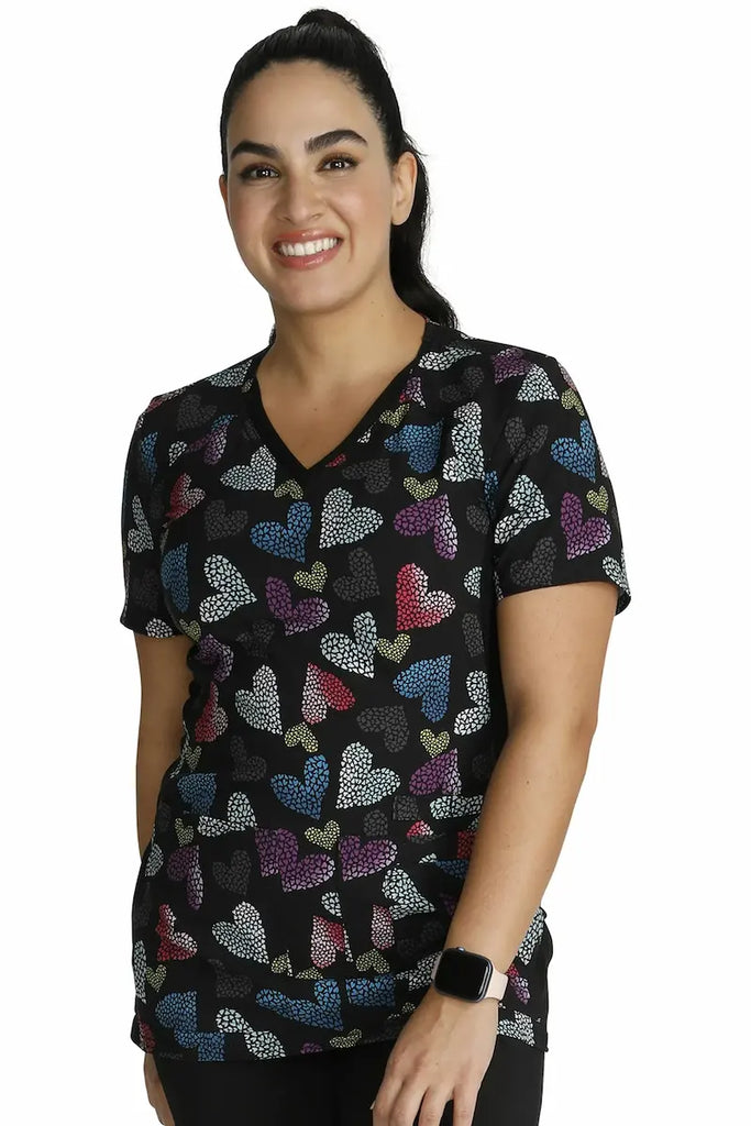 A young female Neonatal Nurse wearing a Cherokee iFlex Women's V-neck Printed Scrub Top in "Loving Glow" size XL featuring a Modern Classic Fit.