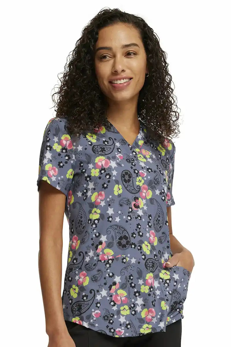 A young female Pediatric Nurse wearing a Cherokee Women's V-neck Printed Scrub Top in "Paisley Petals" size Small featuring a modern classic fit.