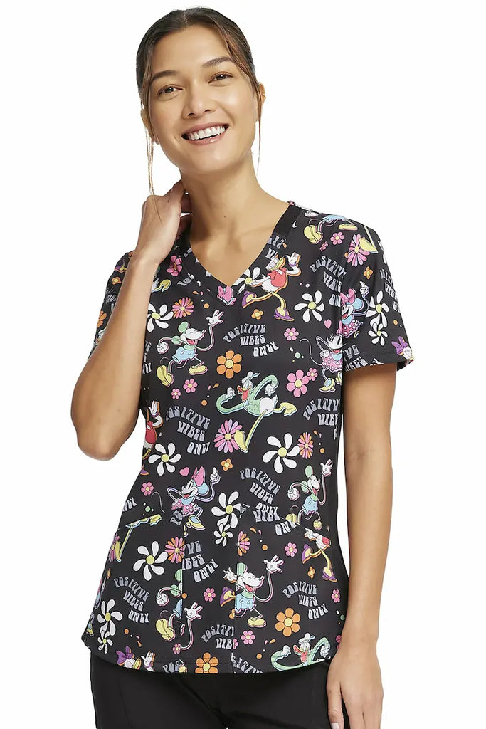 A young female Pediatric Nurse wearing a Tooniforms Women's V-neck Printed Scrub Top in "Positive Vibes" size Small featuring a contemporary fit.