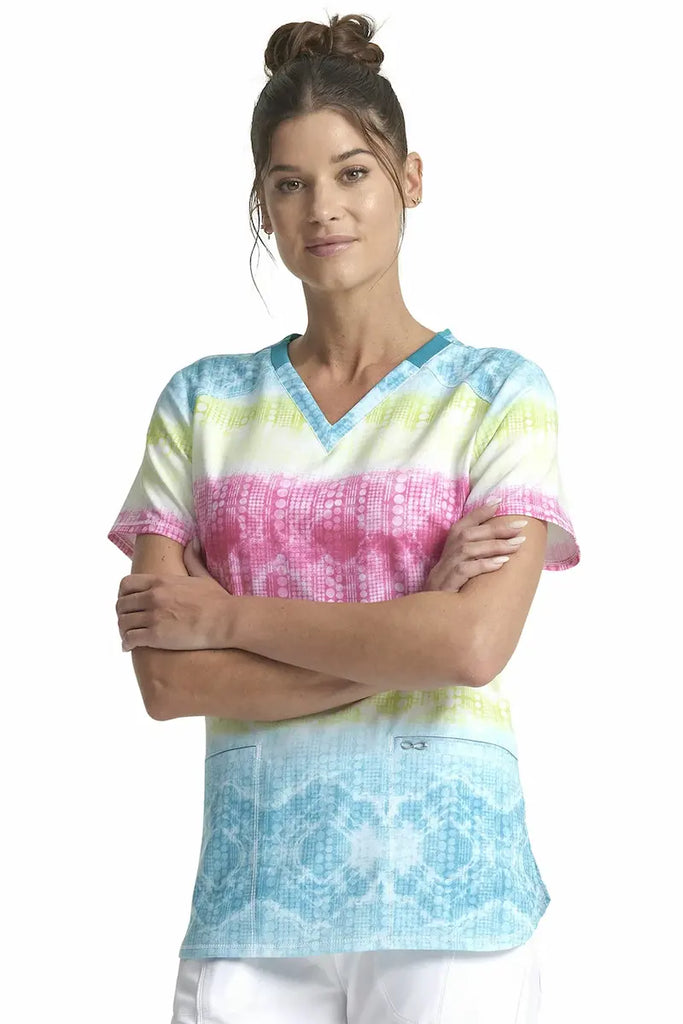 A young female Neonatal nurse wearing a Cherokee Women's V-neck Printed Scrub Top in Trippy Stripes size Medium featuring a modern classic fit.