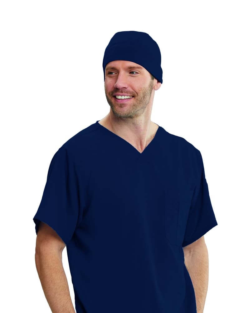 A young male Nursing Assistant wearing a Grey's Anatomy Unisex Fitted Scrub Cap in Navy featuring a silky, moisture wicking fabric.