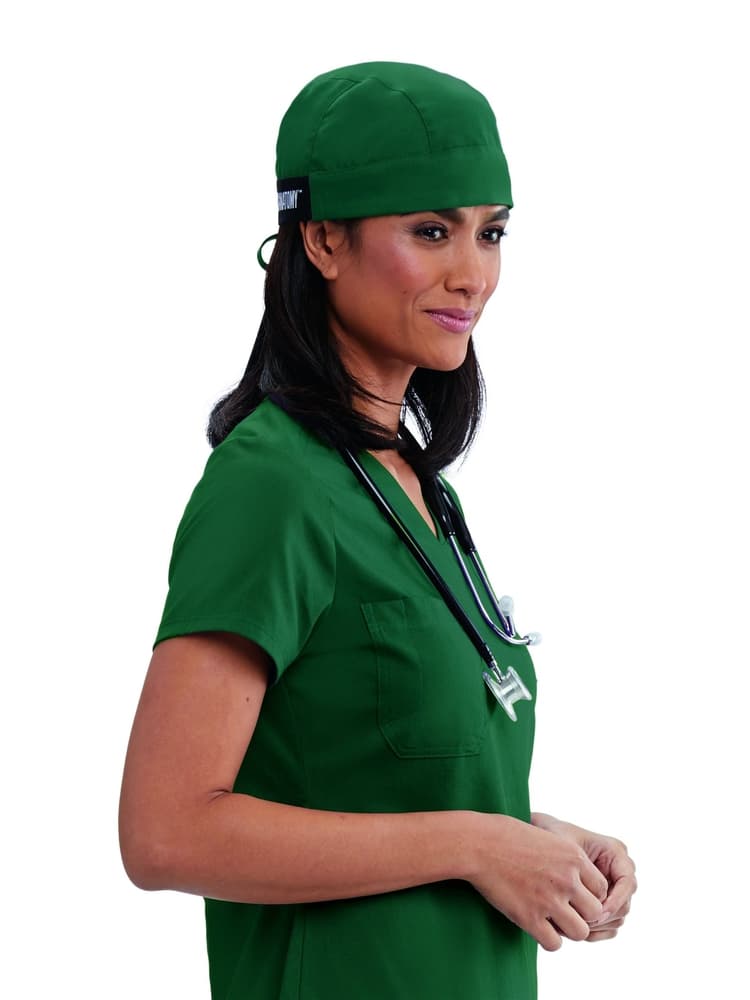 A young female Surgeon wearing a Grey's Anatomy Unisex Fitted Scrub Cap in Hunter Green featuring a self tie at the back to ensure a perfect all day fit.
