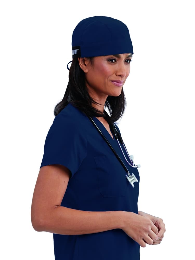 A young female Surgeon wearing a Grey's Anatomy Unisex Fitted Scrub Cap in Indigo featuring a self tie at the back to ensure a perfect all day fit.