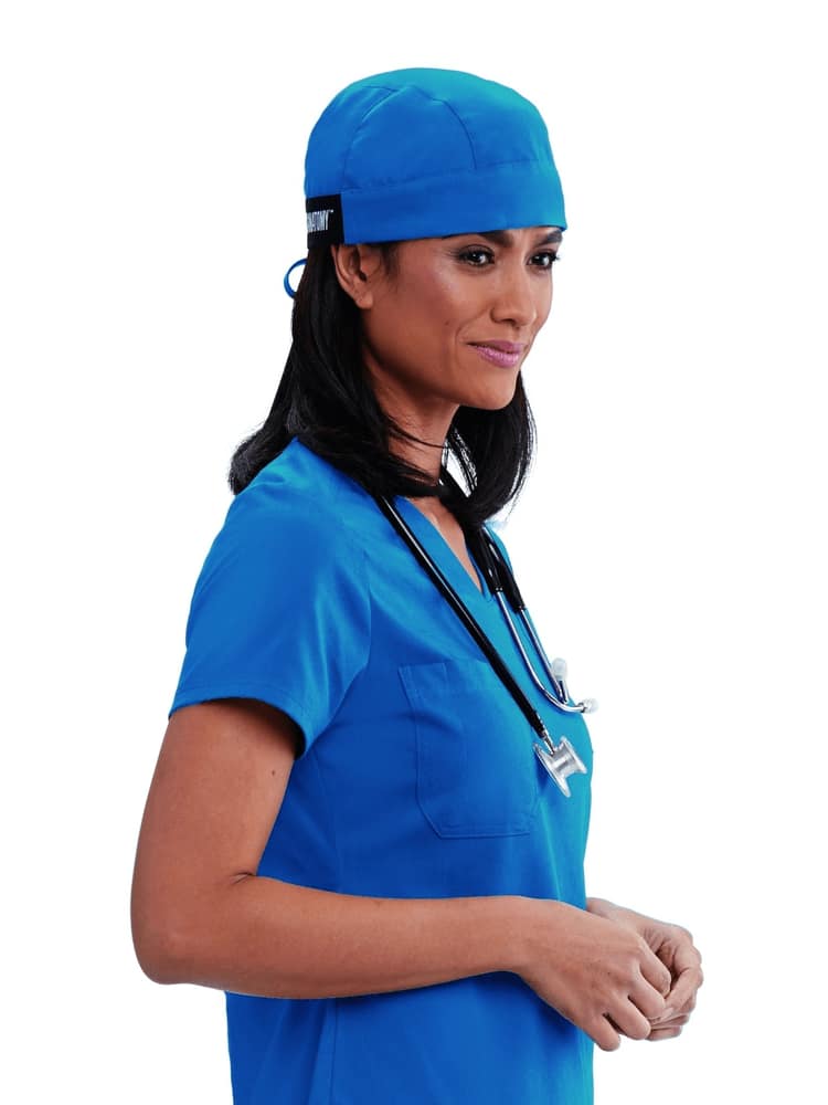 A young female Surgeon wearing a Grey's Anatomy Unisex Fitted Scrub Cap in Royal Blue featuring a self tie at the back to ensure a perfect all day fit.